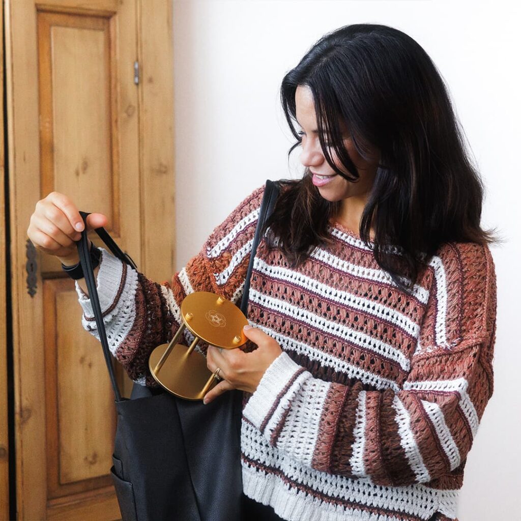 woman in striped sweater placing leelaq travel pad in black bag