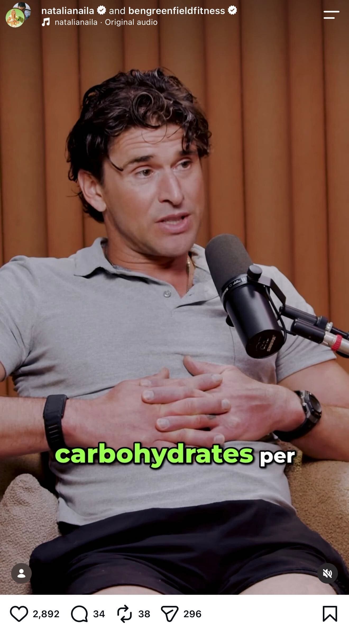 Instagram Reel co-posted by natalianaila and bengreenfieldfitness, using original audio by natalianaila. A man with curly dark brown hair, wearing a gray polo shirt, black shorts, a smartwatch, and a chain necklace, sits on a couch mid-conversation in front of a studio microphone, with a wood-paneled wall behind him. Bold green on-screen caption text reads 'carbohydrates per.'